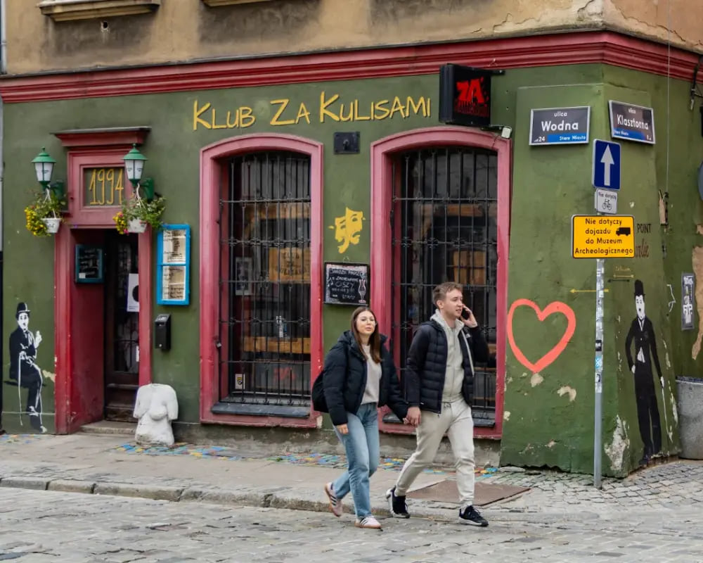 Para idąca przed kolorową fasadą klubu.